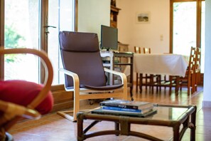 Une pièce comprenant une chaise, une table recouverte d’une nappe blanche et un téléviseur.