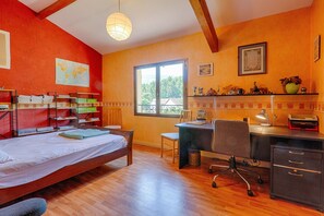 A room with a bed, desk, chair, shelves, and a window with a view.