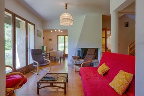 Ein großzügiger Wohnbereich mit einem roten Sofa, einem Glastisch und einem Essbereich mit Stühlen und Tisch.