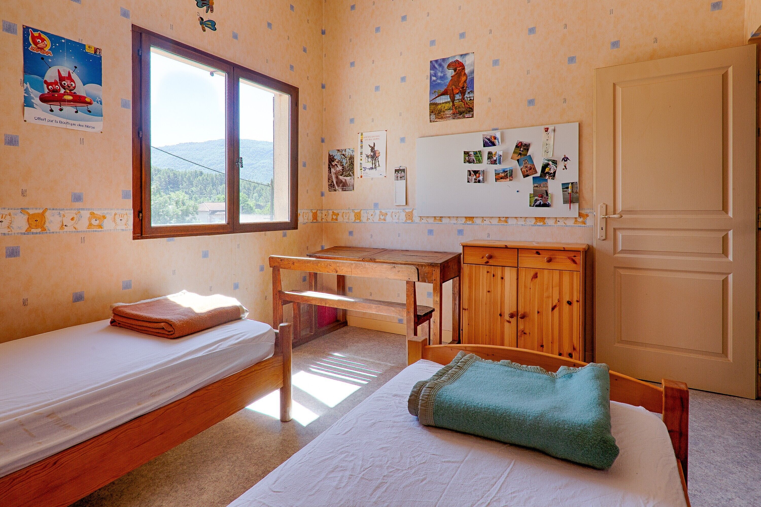 Une chambre avec un lit, un bureau, une armoire et une fenêtre donnant sur un beau paysage.