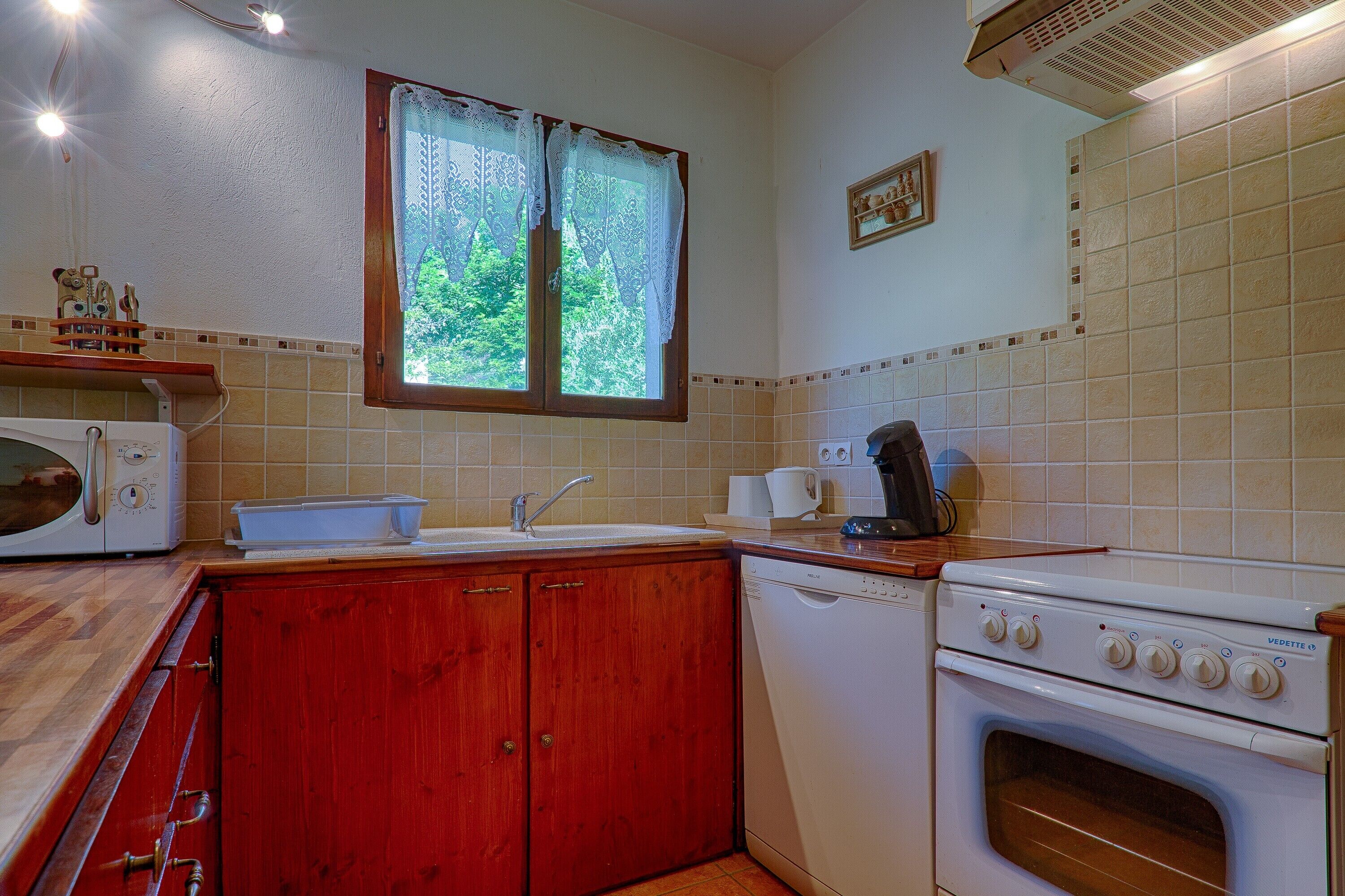 A kitchen with a microwave, sink, stove, and wooden cabinets.