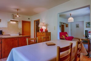 A dining area with a table, chairs, a lamp, and a red chair.