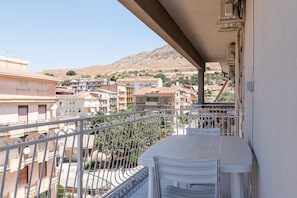 A balcony with a view of a residential area, including buildings and a hill in the background.