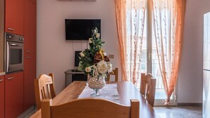A kitchen with red cabinets, a TV, and a dining table with chairs.