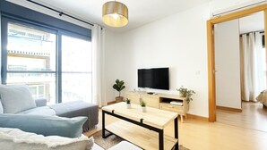 Ein modernes Wohnzimmer mit einer Couch, einem Couchtisch, einem Fernseher und einem Blumentopf.