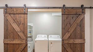A laundry room with a wooden sliding door, a washing machine, and a dryer.