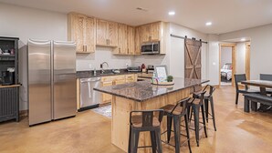A modern kitchen with wooden cabinets, stainless steel appliances, and a central island with bar stools.