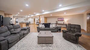 A spacious living room with a grey sofa set, a wooden coffee table, and a patterned rug.