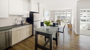 A modern kitchen with white cabinets, a black refrigerator, and a dining area with a table and chairs.
