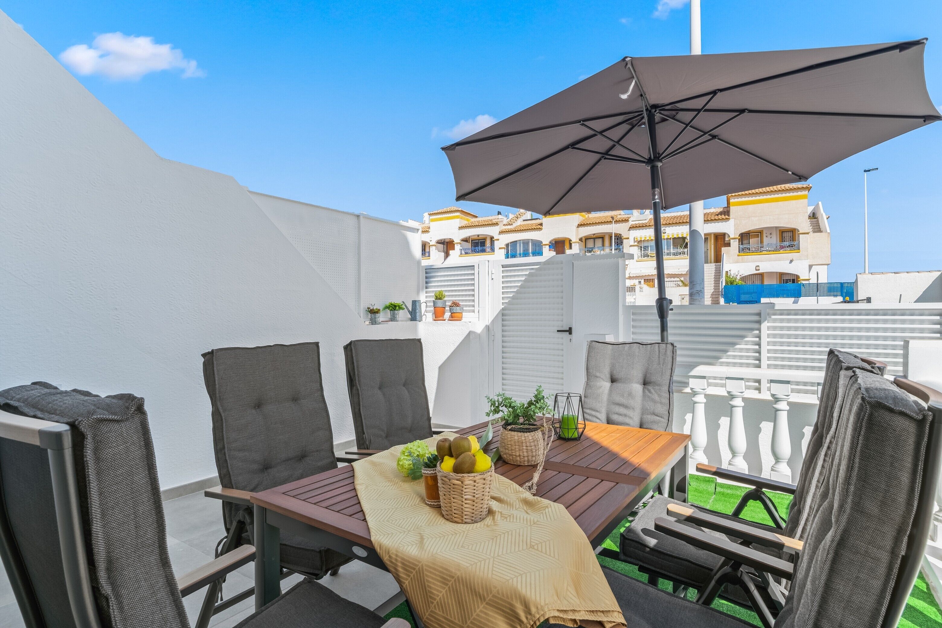 An outdoor dining area with a table, chairs, and an umbrella.