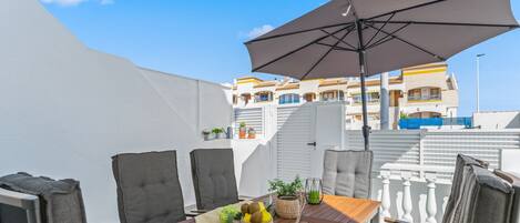An outdoor dining area with a table, chairs, and an umbrella.