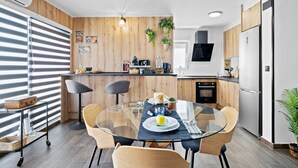 Een moderne keuken met een glazen eettafel, houten details en een ingebouwde oven.
