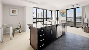 A modern kitchen with a large island, black cabinets, and a view of the city through large windows. - Crystal City 2 BR | 10 min drive to Capitol (Arlington)