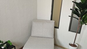 A small, single-bed room with a grey sofa, a potted plant, and a small table. - Singular Reforma (Mexico City)