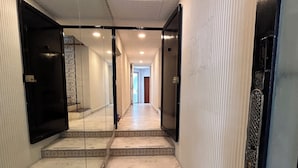 A hallway with a tiled floor, a glass partition, and a door at the end. - Singular Reforma (Mexico City)