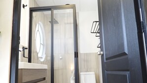 A modern bathroom with a glass-enclosed shower, a white toilet, and a wooden vanity. - Singular Reforma (Mexico City)