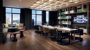 A modern bar area with a long counter, multiple seating options, and a large bookshelf filled with items.