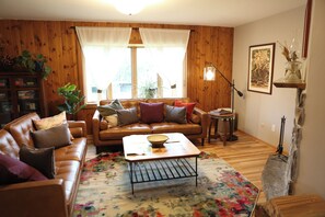 A cozy living room with a leather sofa, a coffee table, and a floral rug.