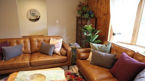 Uma sala de estar com dois sofás de couro marrom, uma mesa de centro de madeira e um tapete floral.
