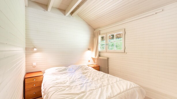 Une chambre à coucher avec un lit, une table de chevet, une fenêtre et un radiateur.