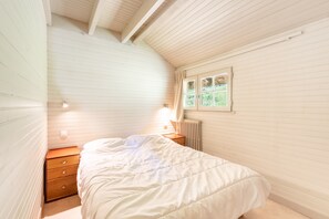 Une chambre à coucher avec un lit, une table de chevet, une fenêtre et un radiateur.