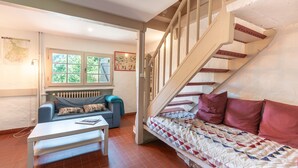 Une pièce comprenant un canapé, une table, un escalier et un radiateur.