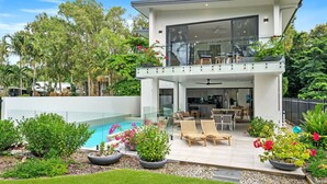 Een modern herenhuis met twee verdiepingen, een glazen balkon, een zwembad en een verzorgde tuin.