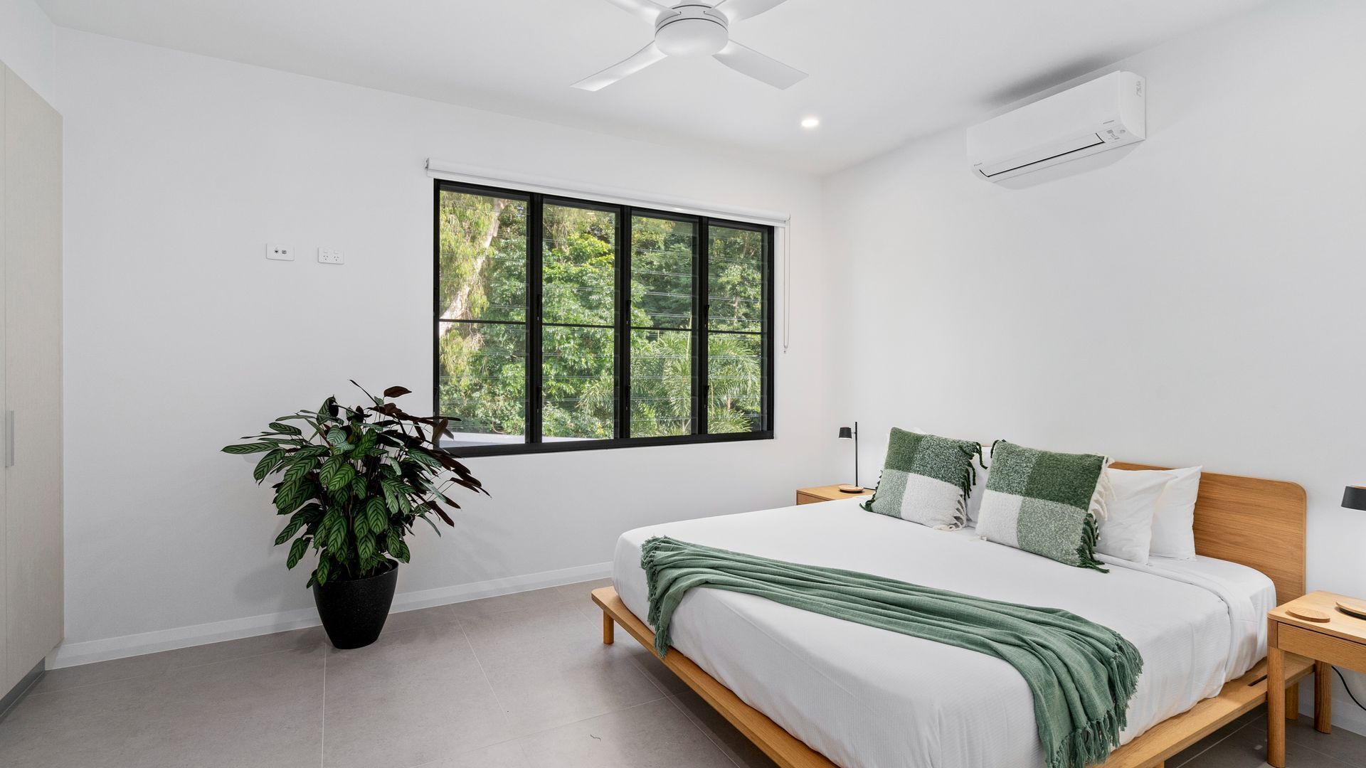 Une chambre moderne avec une grande fenêtre, un ventilateur de plafond et une plante en pot.