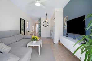 Un salon avec un canapé, une table basse, un téléviseur et une horloge au mur.