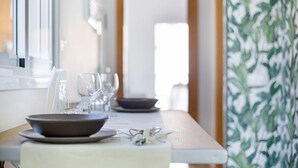 A dining table set with plates, glasses, and cutlery, with a view of a room and a door in the background.