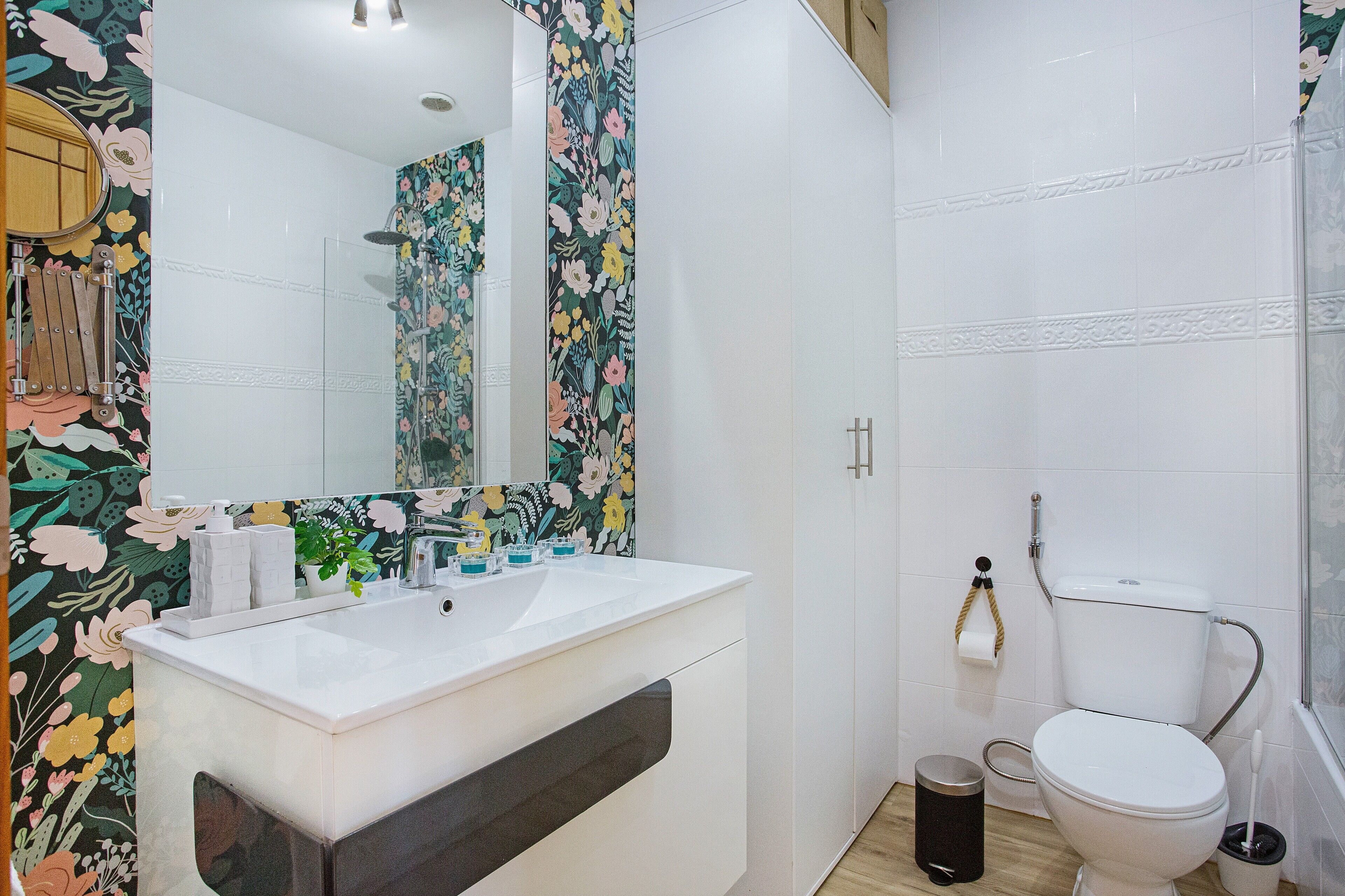 Ein Badezimmer mit weißem Waschbecken, Spiegel, Toilette und Dusche.