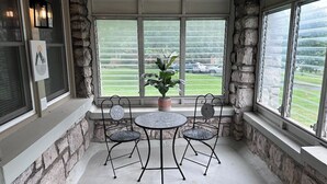 Een overdekt terras met stenen muren, een ronde tafel en vier stoelen.