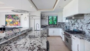 A modern kitchen with white cabinets, a granite countertop, and stainless steel appliances. - Your Private Escape in Punta Mita/Premier membership, HK & Concierge Service (Hacienda de mita)