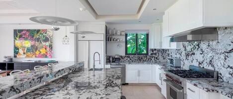 Een moderne keuken met witte kastjes, een granieten aanrechtblad en roestvrijstalen apparatuur.