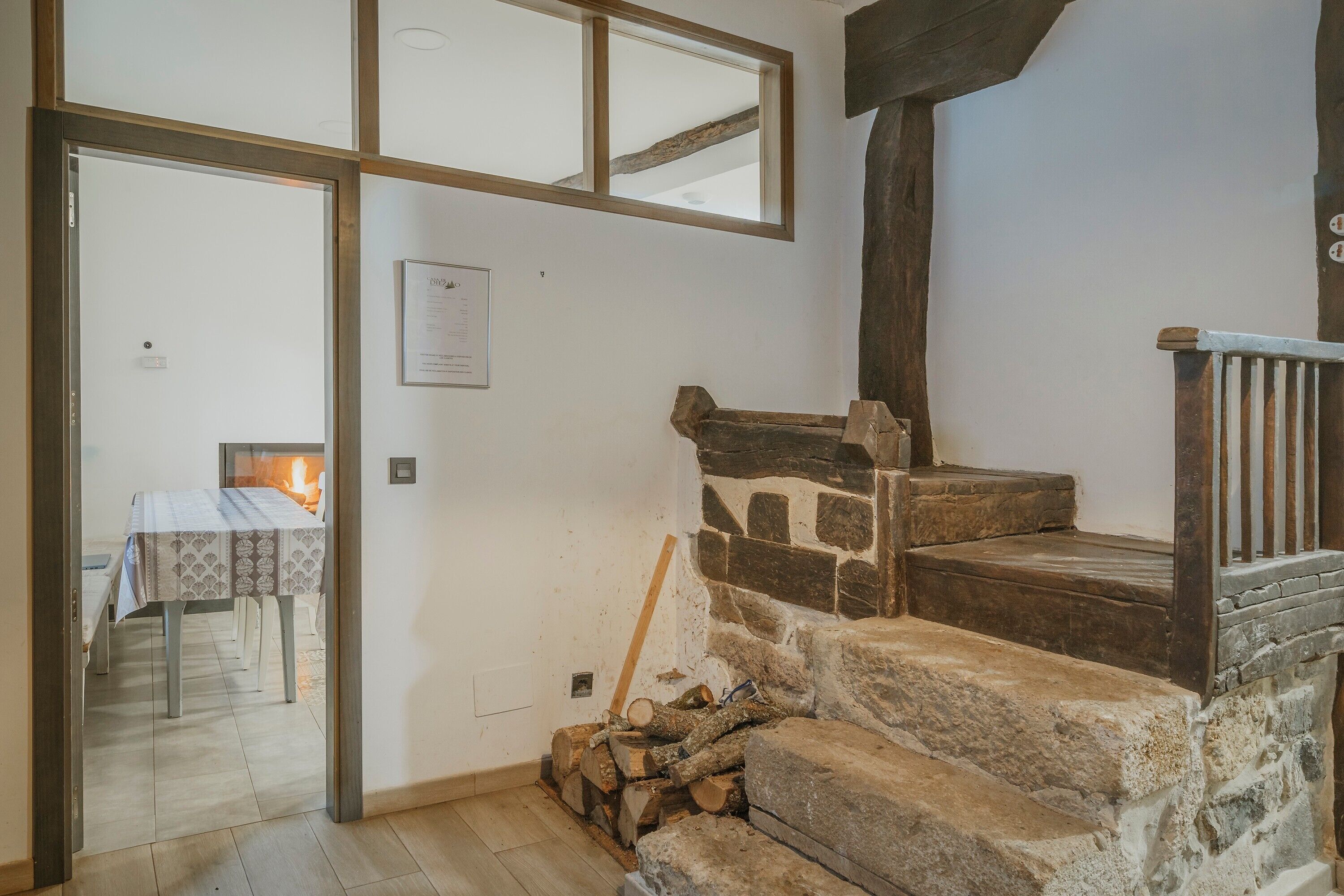 A staircase with stone steps, a wooden railing, and a table with a fire in the background.