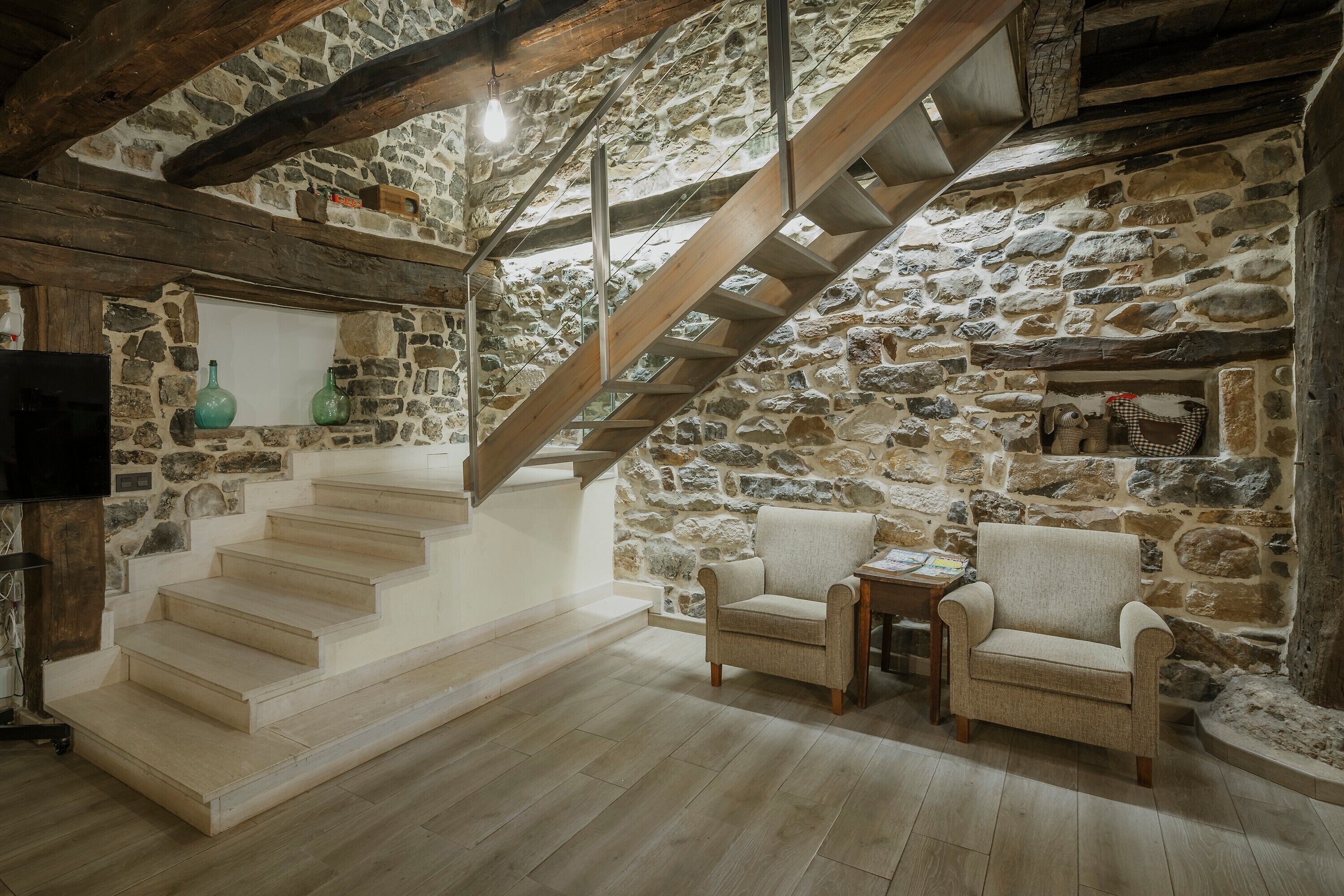 Ein Zimmer mit Stehwänden, einer Holztreppe, zwei Stühlen und einem kleinen Tisch.