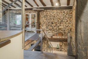 A stone wall, wooden beams, a staircase, and a glass door leading to a room with a view.