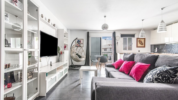 A modern living room with a grey sofa, white shelving, and a flat-screen TV. - Holiday Home 'Bright' with Mountain View, Balcony and Wi-Fi (Agaete)