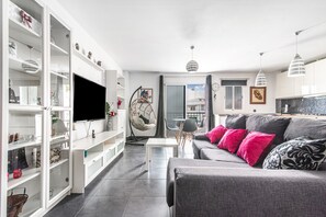 Una sala de estar moderna con un sofá gris, estanterías blancas y un televisor de pantalla plana.