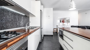 A modern kitchen with a gas stove, white cabinets, a black tiled backsplash, and a wooden countertop. - Holiday Home 'Bright' with Mountain View, Balcony and Wi-Fi (Agaete)