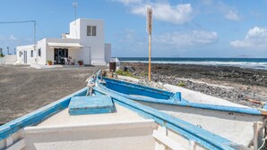 Un edificio costero con fachada blanca, un poste de madera y una fila de barcos azules.