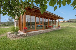 Une structure en bois dotée de grandes fenêtres en verre, d’une fondation en pierre et de plantes en pot.