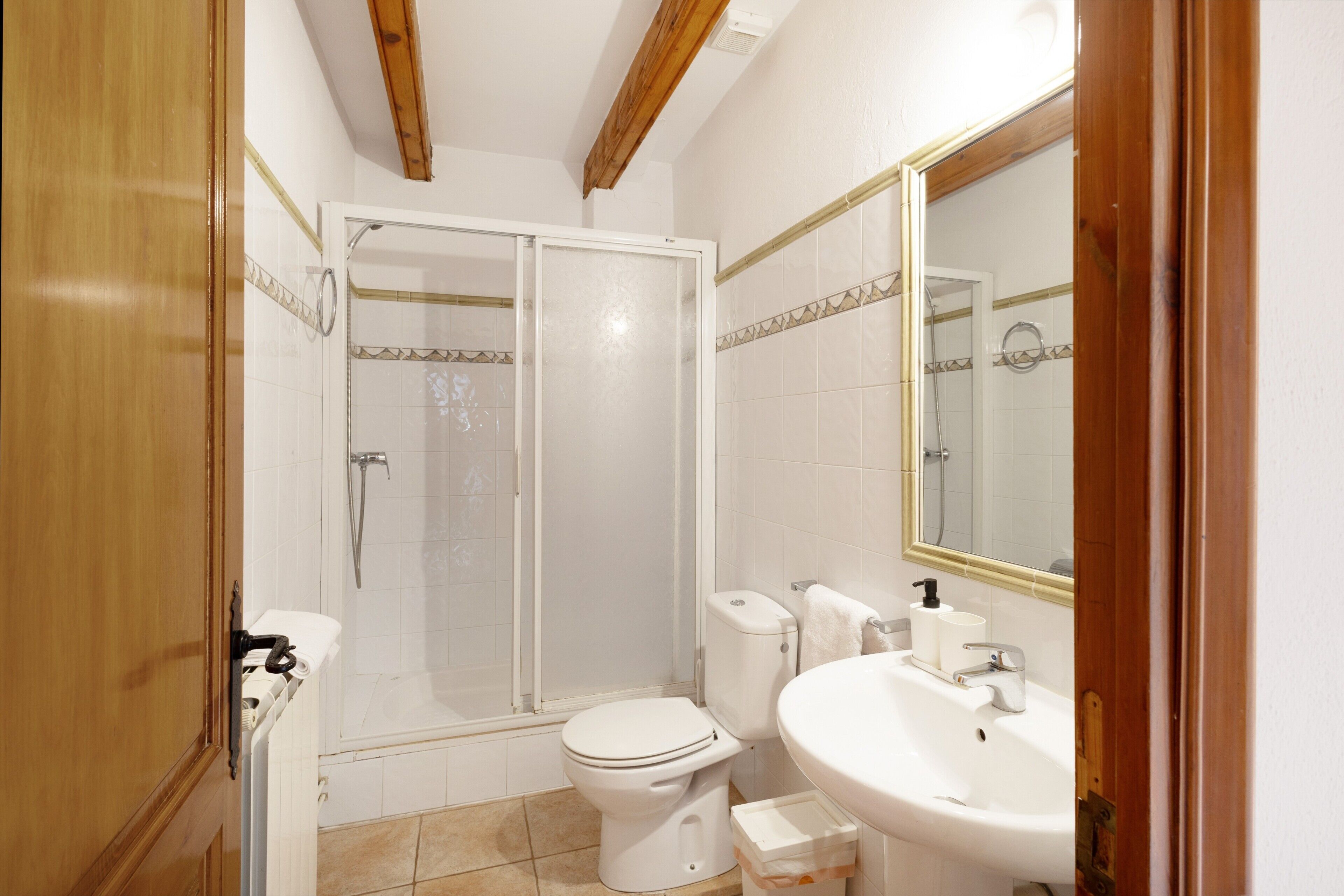Un baño con ducha, inodoro, lavabo y espejo.