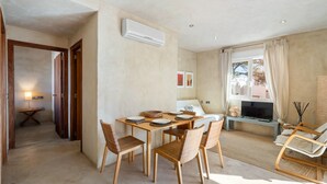Une chambre moderne avec une table à manger dressée pour quatre personnes, un canapé, un téléviseur et une fenêtre avec des rideaux.