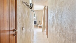 Un couloir avec une porte en bois, un escalier et un lit doté d’une tête de lit.