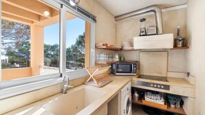 Une cuisine compacte équipée d’un évier, d’un four à micro-ondes et d’une cuisinière. Une fenêtre offre une vue sur l’extérieur.