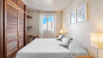 Un dormitorio con cama, armario de madera, ventana con vistas y una obra de arte en la pared.