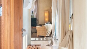 An open doorway leading to a room with a wicker chair, a small table, and a lamp. - Vista Azul Duplex 1 Formentera (La Savina)