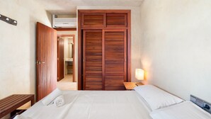 A bedroom with a bed, a wooden wardrobe, a bedside table, and a lamp. - Vista Azul Duplex 1 Formentera (La Savina)