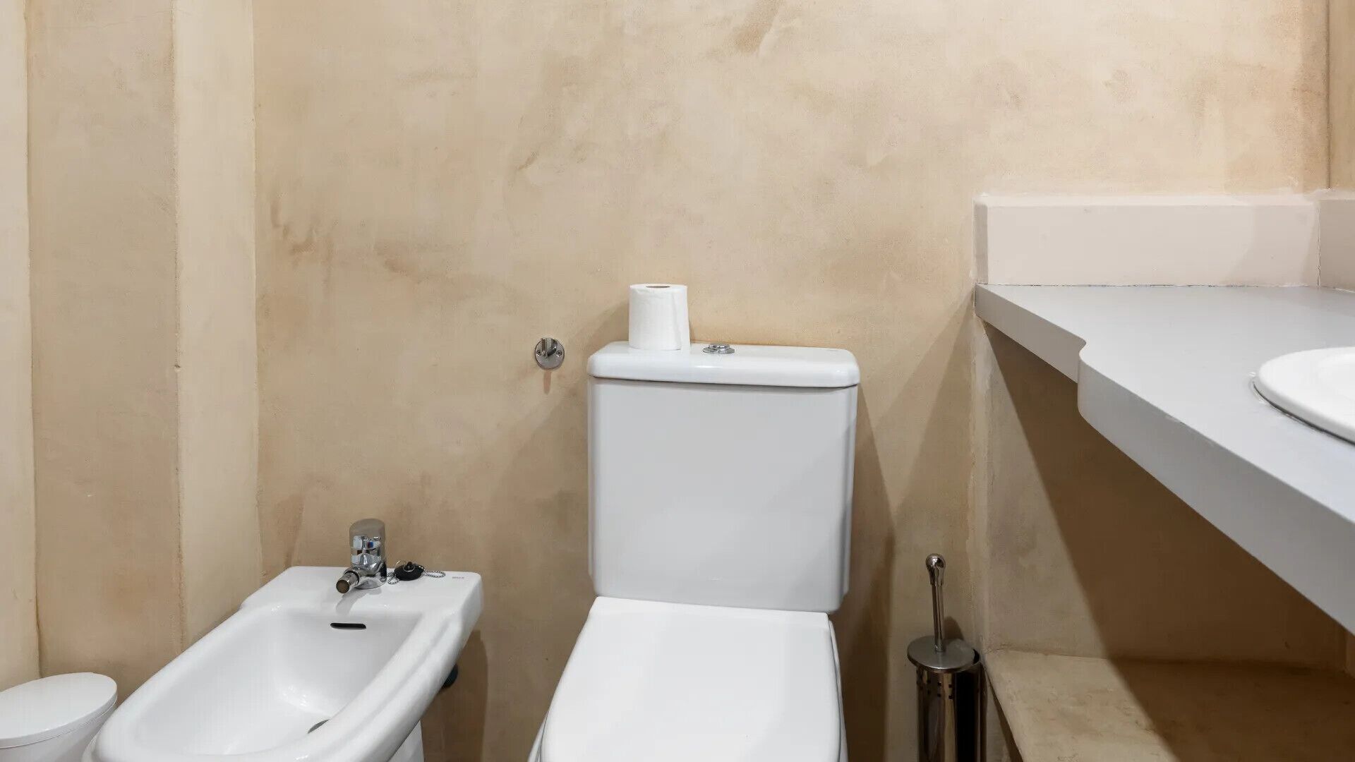 Un baño con inodoro, bidé y lavamanos.